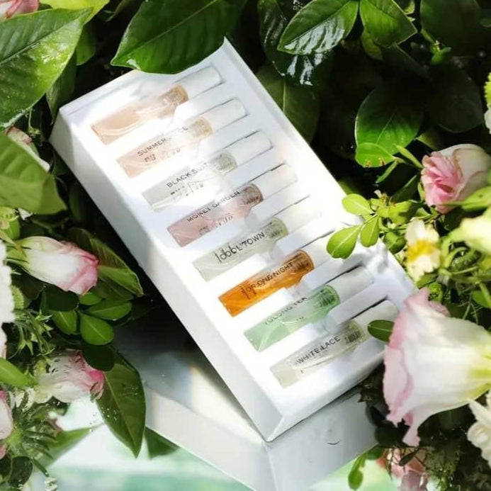 Perfume gift box with eight samples surrounded by flowers and green leaves