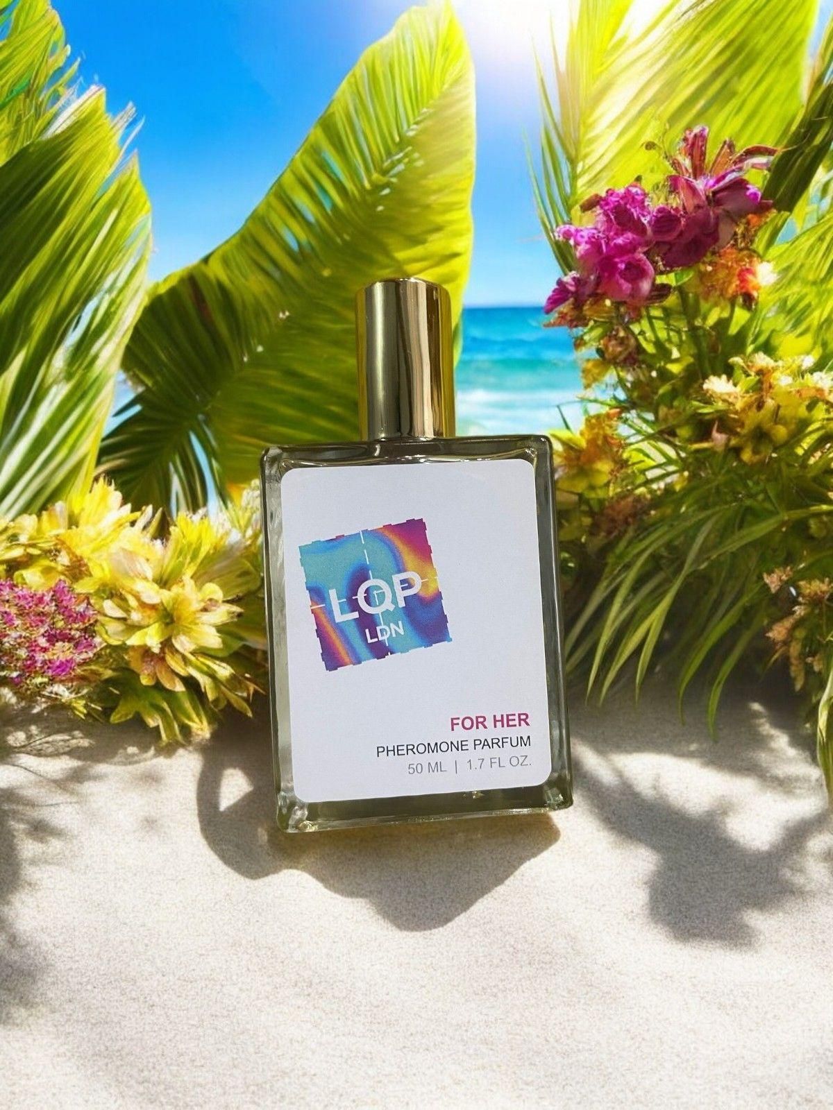 Perfume bottle labeled 'LQP LON' with a colorful logo on a beach setting with flowers and ocean.