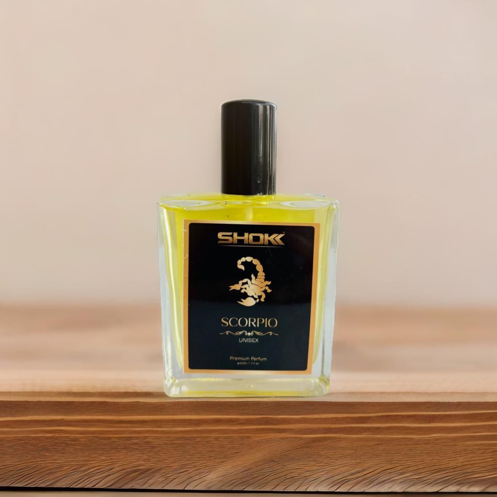 Perfume bottle labeled 'Shokk Scorpio' on a wooden surface with a beige background