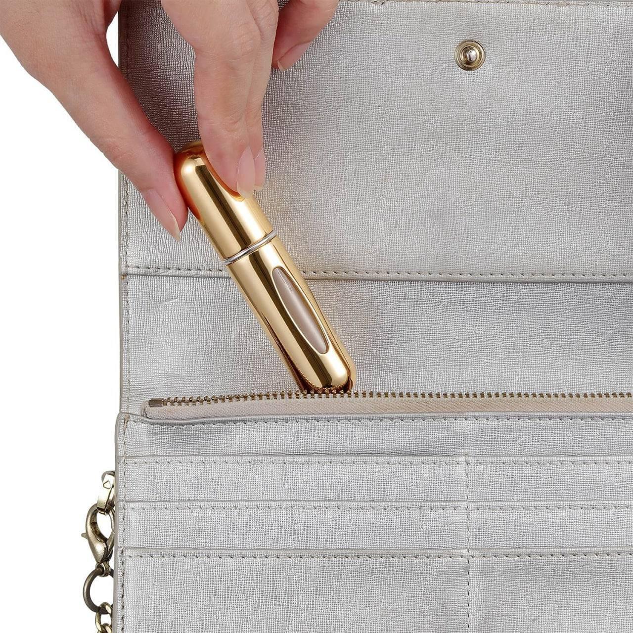 Gold lipstick being placed into a light gray handbag.